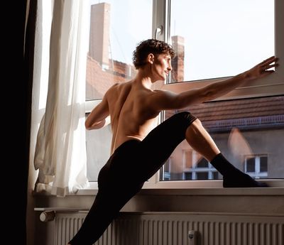 Silhouette of a person stretching against a window.